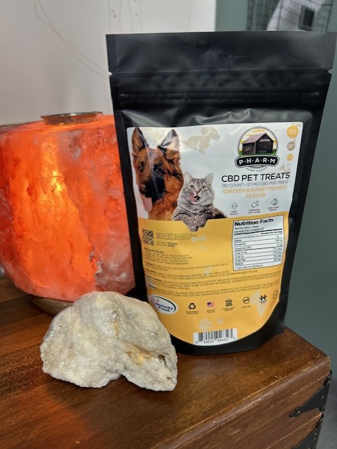 A bag of cat and dog treats next to an orange candle.